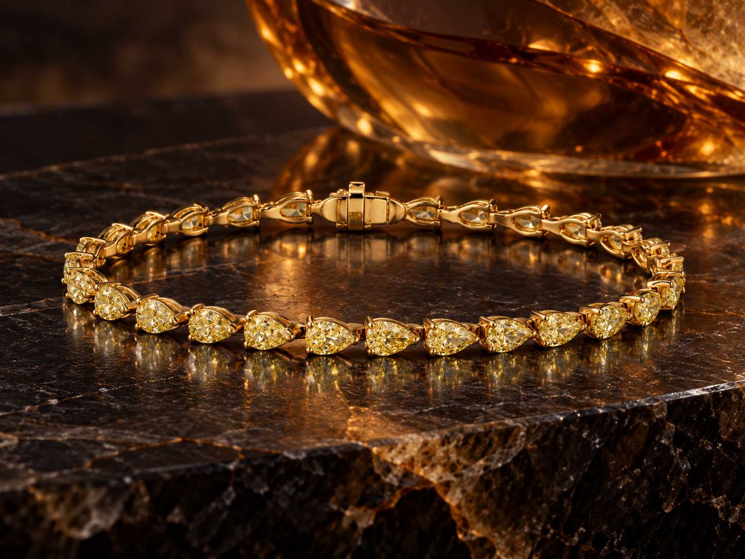 Pear shaped yellow diamond bracelet against dark marble and amber glass